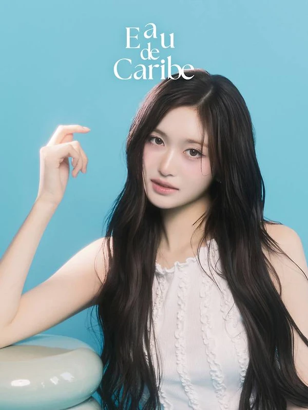 Studio portrait in a white sleeveless top beside a pale green stool.