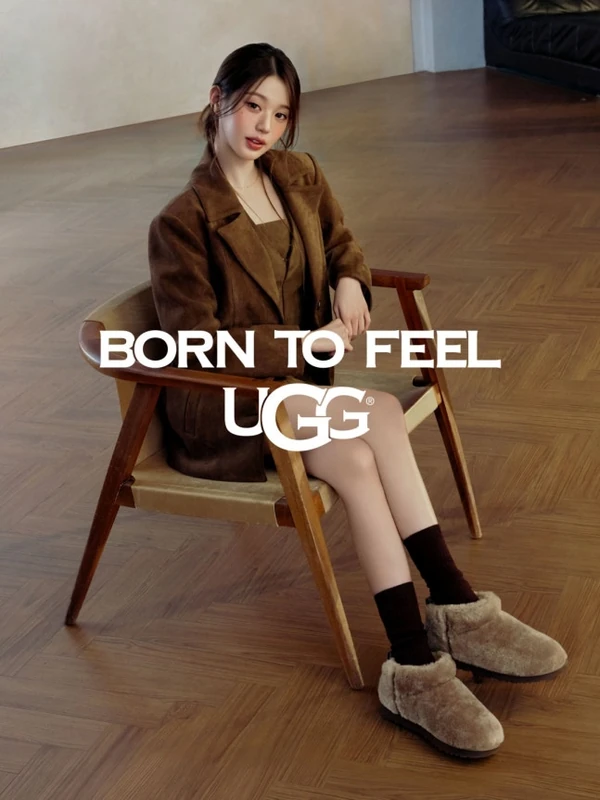 UGG campaign portrait seated in a wooden armchair, wearing a brown jacket, dark socks and fluffy ankle boots.