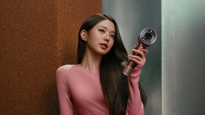 Pink knitwear with straight dark hair and a metallic hairdryer
