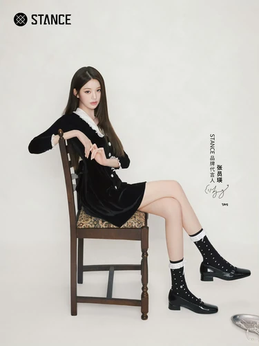 STANCE campaign photograph in a black dress, seated on a wooden chair