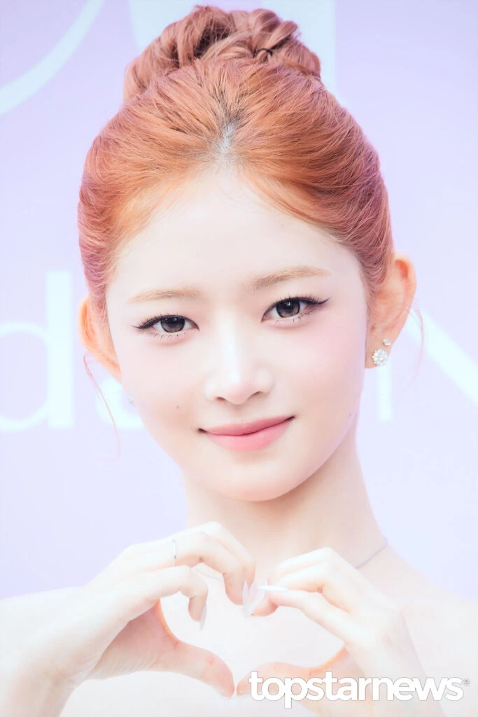 Rei making a heart gesture at the LUNA photo event
