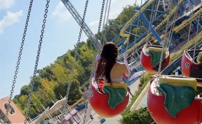 A figure riding a fruit-shaped seat on an amusement-park swing ride
