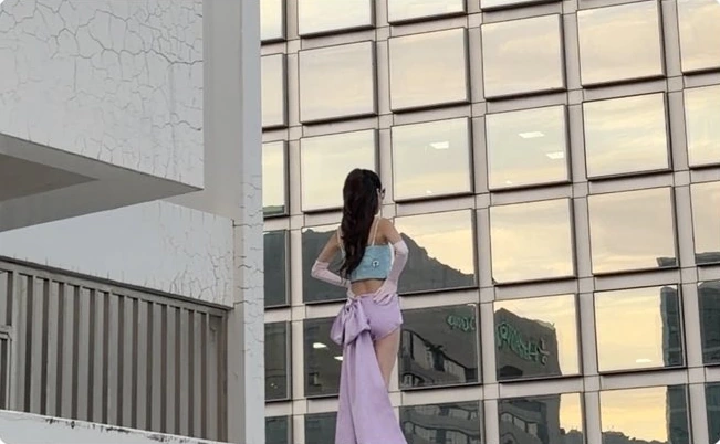 A caped figure against a modern building facade