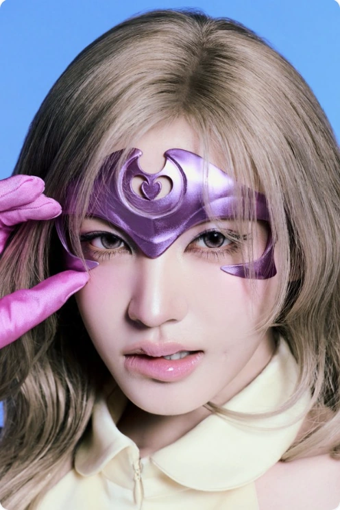 Promotional portrait of Liz wearing a purple headpiece and a pink glove