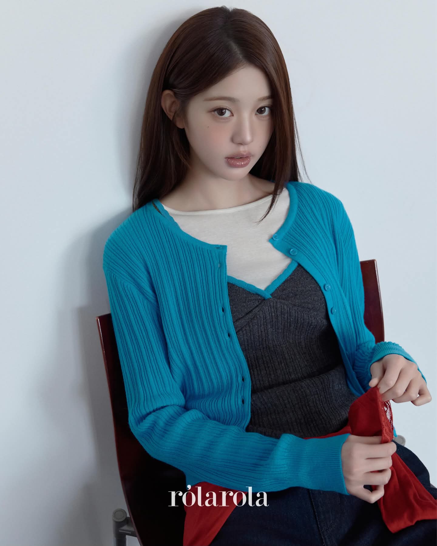 A blue cardigan, charcoal knitwear and a red accent.